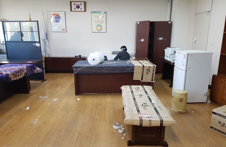사무실 이전 중 랩과 박스로 포장된 임원실 책상과 테이블